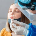 Doctor in protective medical mask taking PCR test nasopharyngeal culture to woman. Diagnostics testing patients coronavirus covid