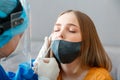 Doctor in protective medical mask taking PCR test nasopharyngeal culture to woman. Diagnostics testing patients coronavirus covid