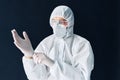 Doctor in protective medical suit puts on protective surgical sterile gloves on his arm Royalty Free Stock Photo