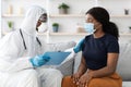 Doctor in protective suit giving recommendations to sick female patient