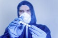 Man in a protective suit and medical mask holds a thermometer in his hands