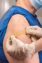 The doctor puts a bandage on the shoulder of an senior patient wearing a mask after giving a dose of the vaccine injection Royalty Free Stock Photo
