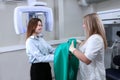 The doctor puts a green protective vest on the patient in the x-ray room. X-ray equipment in the clinic. Modern medicine