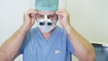 Doctor puts on magnifying binocular glasses and adjusts them, preparing for surgery in clinic