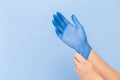 The doctor puts on sterile gloves on a blue background. Infection control concept.