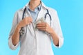 Doctor putting bribe money into pocket on blue background, closeup. Corruption in medicine Royalty Free Stock Photo