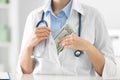 Doctor putting bribe into pocket at desk in clinic. Corrupted medicine Royalty Free Stock Photo