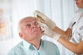 Doctor putting drops into a senior man's eyes