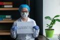 Doctor with Quarantine inscription on white blank. Female Medic in protective mask and uniform looks at camera standing