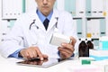 Doctor reading a Digital Tablet with drug boxes in hand Royalty Free Stock Photo