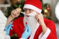 Doctor in rubber gloves taking nasal swab of pcr for santa claus near christmas tree
