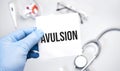 The doctor's blue - gloved hands show the word avulsion - . a gloved hand