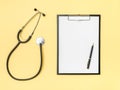 Doctor`s desk top view. Stethoscope and notebook on a colored background