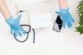 The doctor`s gloved hands hold the mask. Keyboard, stethoscope, phone, mask, gloves. Top view. Royalty Free Stock Photo