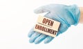 Doctor`s hand in blue glove shows the wooden cubes with text OPEN ENROLLMENT. Medical concept