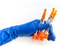 Doctor`s hand in blue medical glove holding several syringes with medical solution white isolated background. Flu Royalty Free Stock Photo