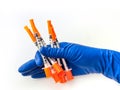 Doctor`s hand in blue medical glove holding several syringes with medical solution white isolated background. Flu Royalty Free Stock Photo