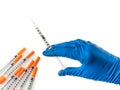 Doctor`s hand in blue medical glove holding syringe with medical solution. Several empty syringes are nearby on white Royalty Free Stock Photo