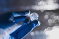 A Doctor`s hand in blue medical gloves holding syringe and vaccine. Royalty Free Stock Photo