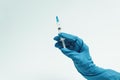 Doctor`s hand in a blue rubber glove holds a medical syringe on a blue background. The concept of medicine and medical care for Royalty Free Stock Photo