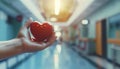 Doctor's hand holding a red heart shape in a hospital. love, donor, world heart day by AI generated image Royalty Free Stock Photo