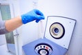 doctor`s hand holds an empty capsule over a medical centrifuge in the dentistry office