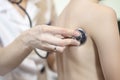 Doctor`s hand holds the stethoscope head attached to the back of the child during lung examination.