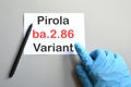 Doctor's hand indicate white sheet with text ba.2.86 Pirola Variant.