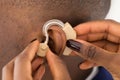 Doctor's Hand Inserting A Hearing Aid Into A Man's Ear