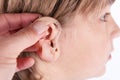 Doctor`s hand inserting a hearing aid in a young boy`s ear. Royalty Free Stock Photo