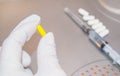 A doctor`s hand in white disposable medical rubber gloves holds a pill capsule against the background of a medicine syringe, an Royalty Free Stock Photo