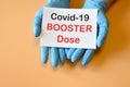 The doctor`s hands hold a paper with text `Covid-19 Booster Dose`. Concept of combating the COVID-19 and new variants virus wit