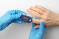 Doctor`s hands in medical gloves put a pulse oximeter on the finger of an elderly woman. Saturation measurement in a 60-year-old Royalty Free Stock Photo