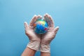 Doctor`s hands in medical surgical gloves holding earth globe on blue background Royalty Free Stock Photo