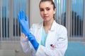 Doctor`s hands putting on latex gloves in a hospital. Woman in a doctor`s smock in latex gloves. Protection against Royalty Free Stock Photo