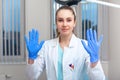 Doctor`s hands putting on latex gloves in a hospital. Woman in a doctor`s smock in latex gloves. Protection against Royalty Free Stock Photo