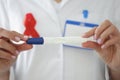 Doctor`s hands with red ribbon on his chest hold pregnancy test closeup