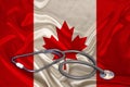 DoctorÃ¢â¬â¢s tool, medical stethoscope, lies on the silk national flag of the state of Canada, the concept of tourism, insurance,