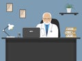 Doctor`s workplace. An elderly male doctor in a white robe is sitting at the table