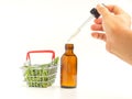 Doctor or Scientist hand holding of cannabis extraction oil bottle and marijuana leaves and male buds flower in a mini basket