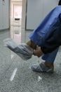 Doctor seated putting on protective boots on her feet.