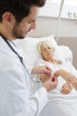 doctor securing identification tag on senior female patient in hospital