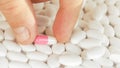 The doctor selected a bright pink and white capsule from all the white tablets and took it with his fingers without Royalty Free Stock Photo