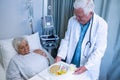 Doctor serving breakfast and medicine to senior patient