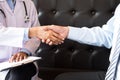 Doctor shakes hands at medical office with patient, wearing glasses, stethoscope and lab coat Royalty Free Stock Photo