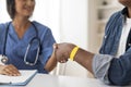 Doctor shaking hands with male patient wearing hospital wristband during medical appointment Royalty Free Stock Photo