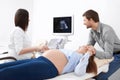 Doctor showing first baby photo and screening stomach of woman. Royalty Free Stock Photo