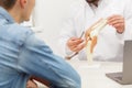 Doctor showing flexible knee joint model to his patient and explains the cause of his pain in medical office. Patient Royalty Free Stock Photo