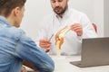 Doctor showing flexible knee joint model to his patient and explains the cause of his pain in medical office. Patient Royalty Free Stock Photo