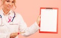 Doctor showing folder with pink ribbon by pen. Royalty Free Stock Photo